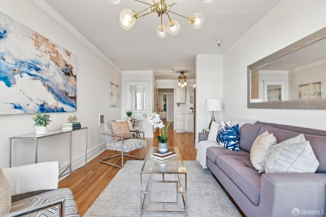 living room featuring an inviting chandelier, crown molding, and light wood-type flooring