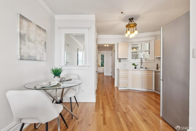 dining space with sink, an inviting chandelier, and light wood-type flooring