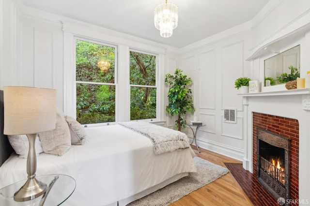 bedroom featuring dark wood-type flooring, a fireplace, and a chandelier