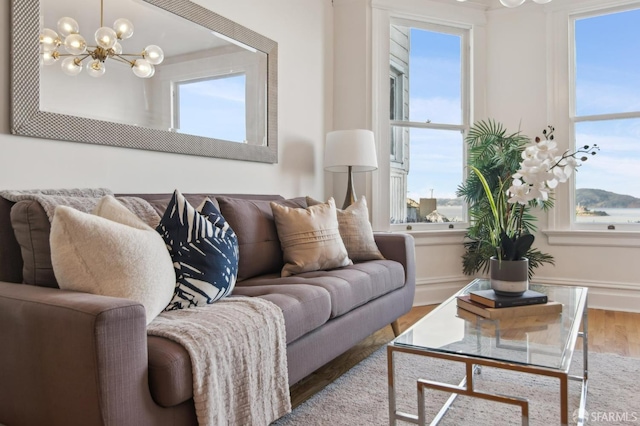 living room featuring a wealth of natural light, a notable chandelier, and light hardwood / wood-style floors