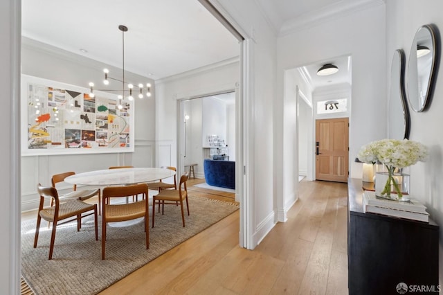 dining space with ornamental molding, light wood-style flooring, and a decorative wall
