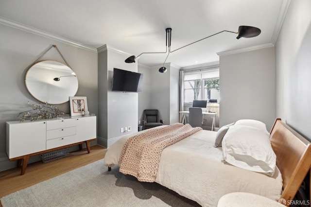 bedroom with crown molding, baseboards, and wood finished floors