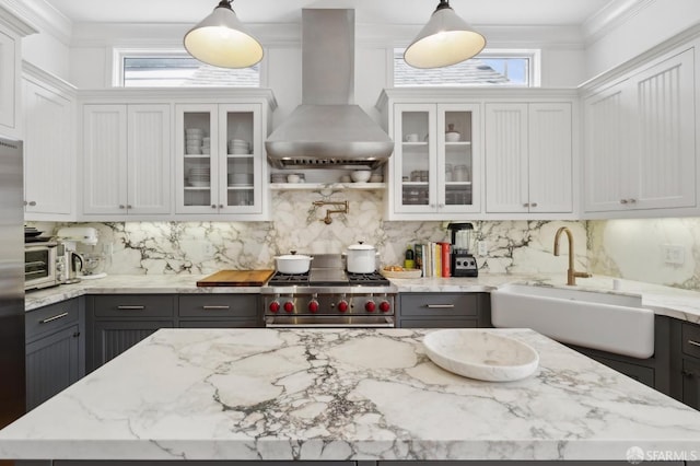 kitchen with a sink, high end stainless steel range, ventilation hood, and tasteful backsplash