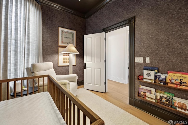 bedroom featuring ornamental molding, wallpapered walls, and wood finished floors