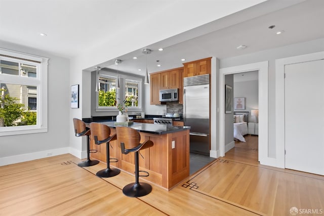 2195 Green St Unit 2, San Francisco, CA 94123 - kitchen with dark countertops, a breakfast bar area, stainless steel appliances, baseboards, and wood finished floors