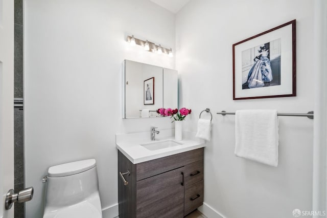 bathroom with baseboards, toilet, and vanity