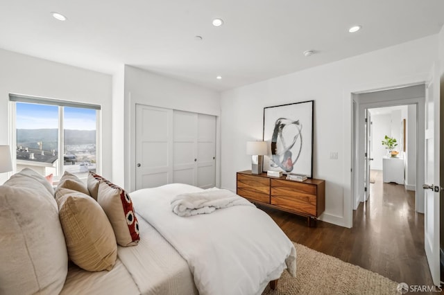 bedroom with recessed lighting, dark wood-style floors, and a closet