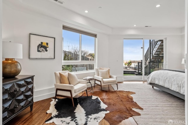 bedroom with multiple windows, wood finished floors, baseboards, and access to outside