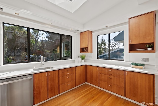 kitchen with brown cabinets, dishwasher, light wood-style flooring, and a sink