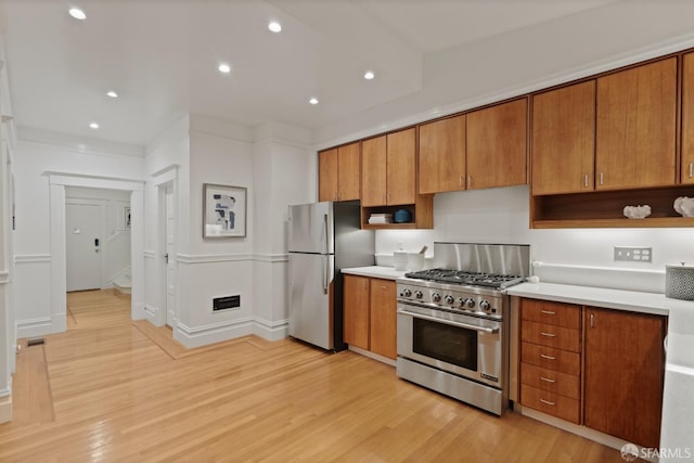 kitchen with light wood-style flooring, recessed lighting, stainless steel appliances, brown cabinetry, and light countertops