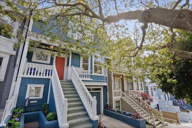 view of front of home featuring stairway, covered porch, and driveway