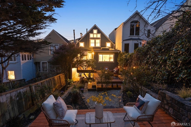 back of house featuring an outdoor living space, a deck, and fence