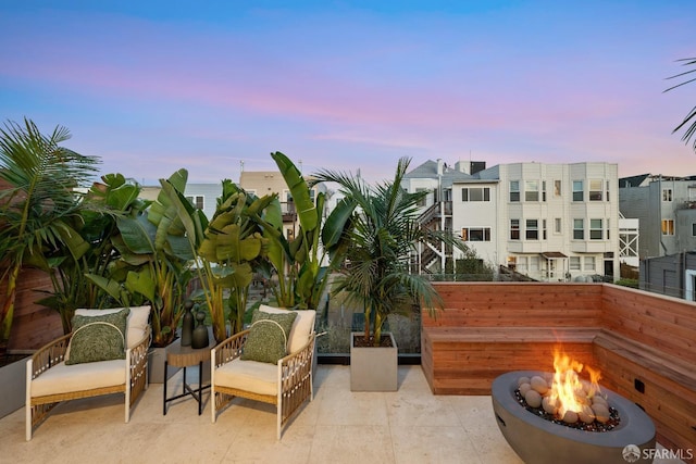 balcony at dusk featuring a patio area and an outdoor fire pit