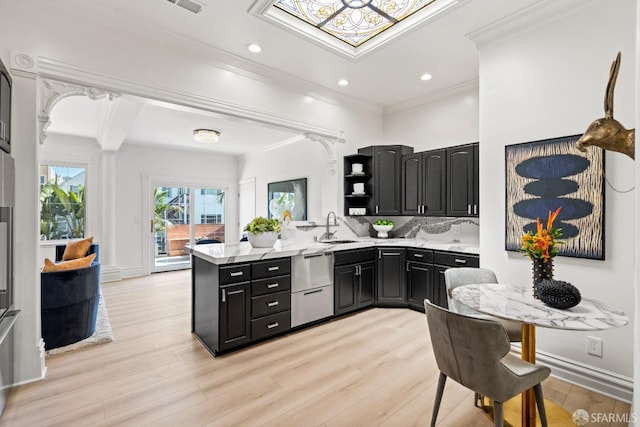 kitchen featuring light wood finished floors, open shelves, dishwasher, dark cabinetry, and a sink