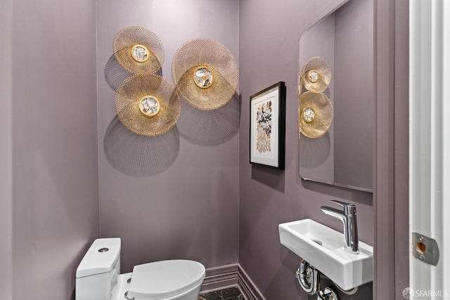 bathroom featuring toilet, baseboards, and a sink