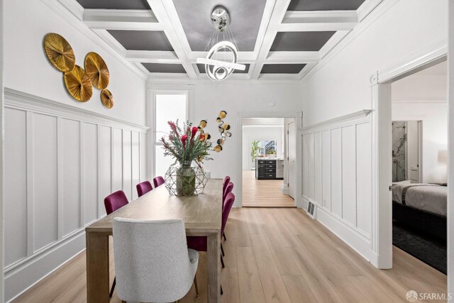 dining room with beamed ceiling, ornamental molding, coffered ceiling, and light wood-type flooring