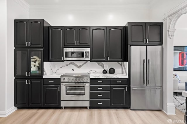 kitchen featuring crown molding, high quality appliances, light wood-style floors, and dark cabinets