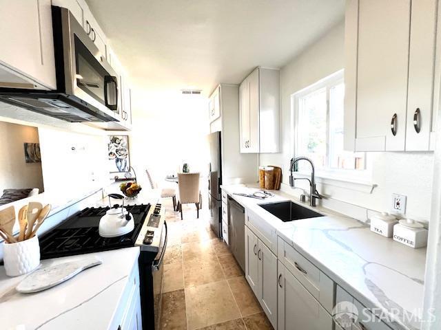 590 Hurlingame Ave, Redwood City, CA 94063 - kitchen featuring a sink, appliances with stainless steel finishes, light stone countertops, and white cabinets