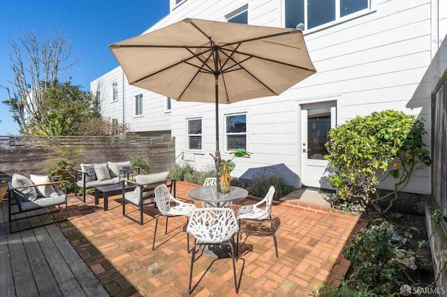 view of patio featuring outdoor dining area, fence, and an outdoor living space