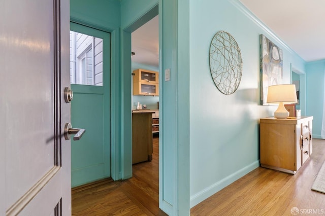 corridor featuring crown molding, baseboards, and wood finished floors