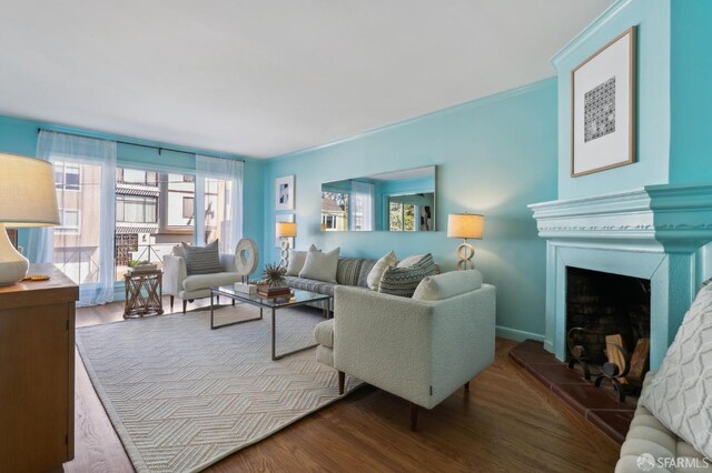 living area featuring ornamental molding, a fireplace with raised hearth, and wood finished floors