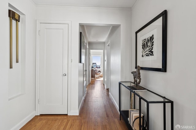 hall with crown molding, baseboards, and wood finished floors