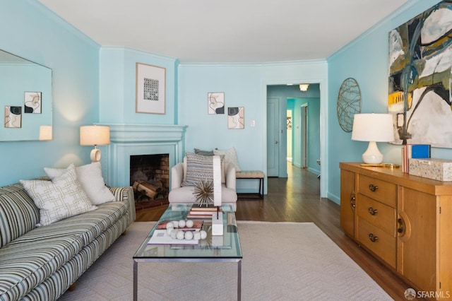 living area with baseboards, a fireplace, wood finished floors, and crown molding