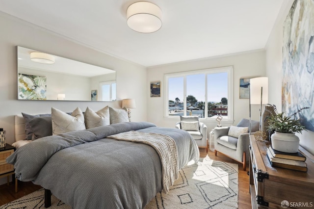 bedroom with ornamental molding and wood finished floors