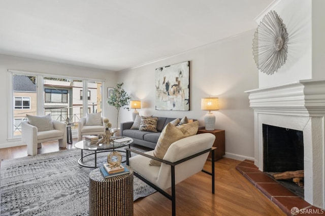 living area with baseboards, a fireplace with raised hearth, and wood finished floors