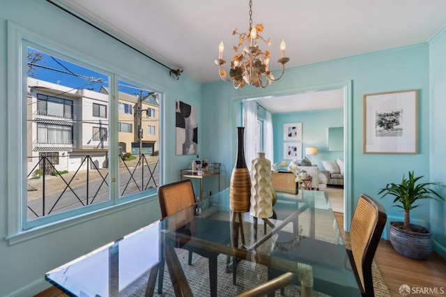 dining area featuring baseboards, a chandelier, and wood finished floors