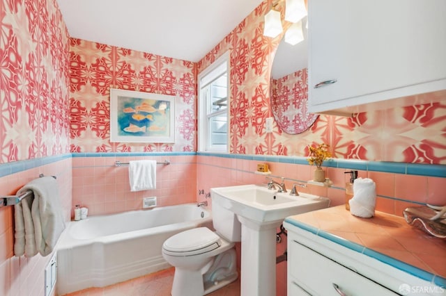 full bath with toilet, wainscoting, a bath, and wallpapered walls