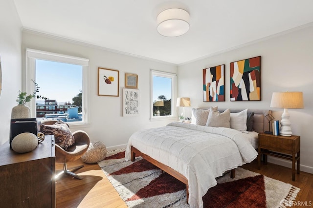 bedroom featuring ornamental molding, baseboards, and wood finished floors