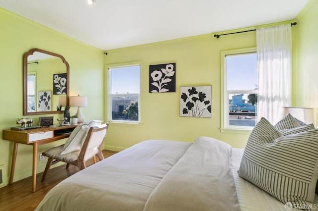 bedroom with ornamental molding, wood finished floors, and baseboards