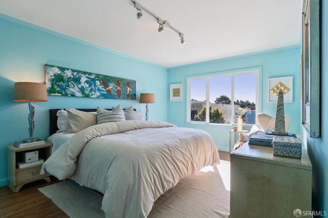 bedroom with ornamental molding, wood finished floors, and baseboards