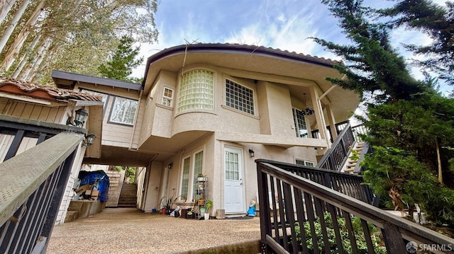 rear view of house featuring stucco siding and stairs