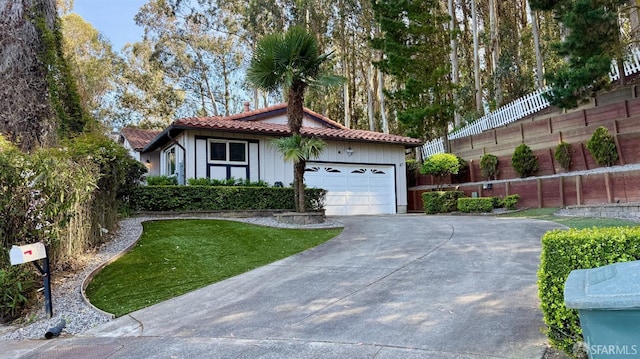 view of front facade with a tiled roof, a garage, fence, concrete driveway, and a front lawn