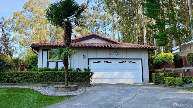 view of front of property with a tile roof, a garage, and driveway