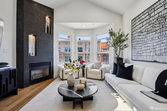 living room featuring a fireplace, light wood-type flooring, and lofted ceiling