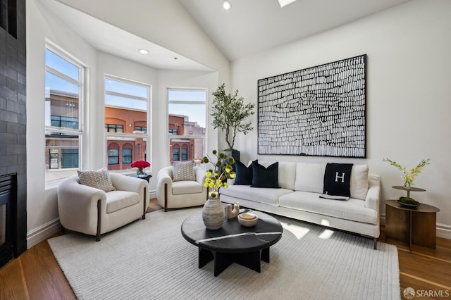 living room featuring a tile fireplace, wood-type flooring, and lofted ceiling