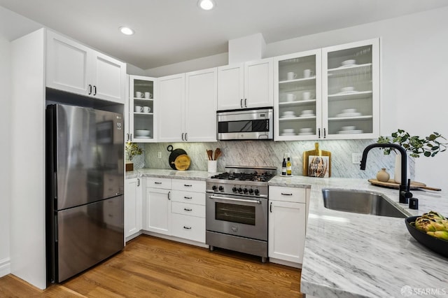 kitchen featuring white cabinetry, light stone counters, sink, and appliances with stainless steel finishes