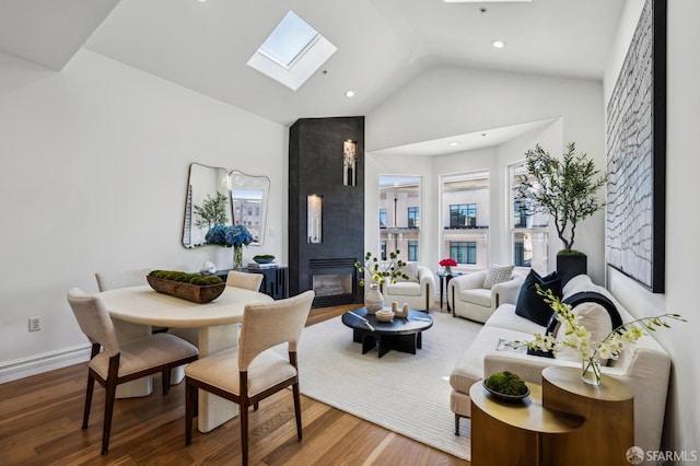 living room with vaulted ceiling with skylight, a large fireplace, and hardwood / wood-style flooring