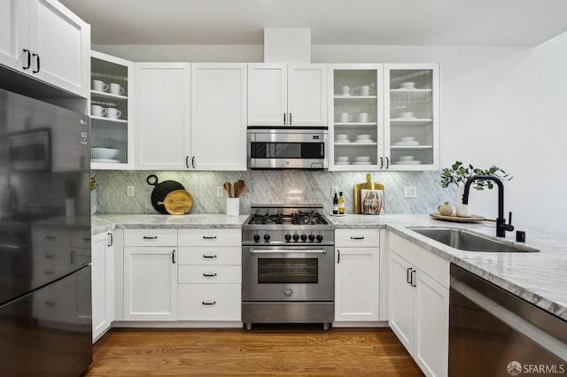 kitchen with light stone countertops, white cabinetry, sink, and stainless steel appliances