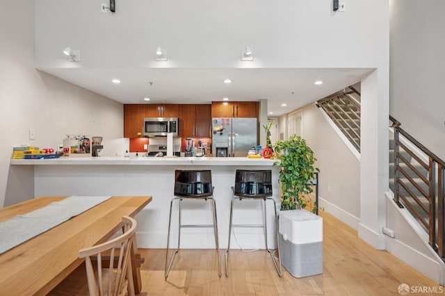 700 Illinois St Unit 3, San Francisco, CA 94107 - kitchen with appliances with stainless steel finishes, brown cabinets, a peninsula, light wood-style floors, and light countertops