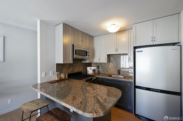 kitchen featuring a kitchen bar, sink, kitchen peninsula, and appliances with stainless steel finishes