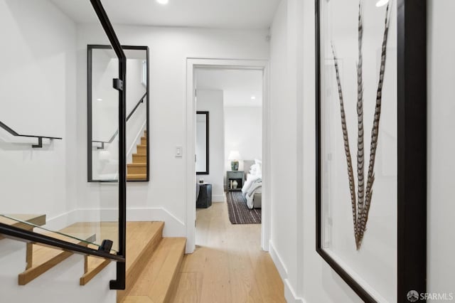 hall with stairs, baseboards, and light wood-type flooring