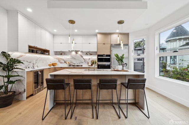 kitchen featuring modern cabinets, wine cooler, appliances with stainless steel finishes, light countertops, and decorative backsplash