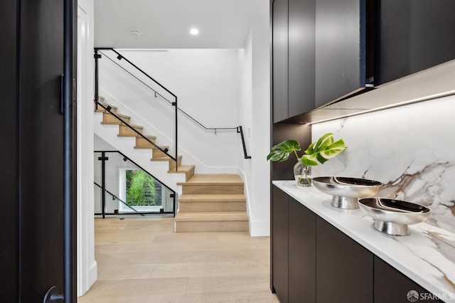 bar with recessed lighting, decorative backsplash, light wood-style flooring, and stairs