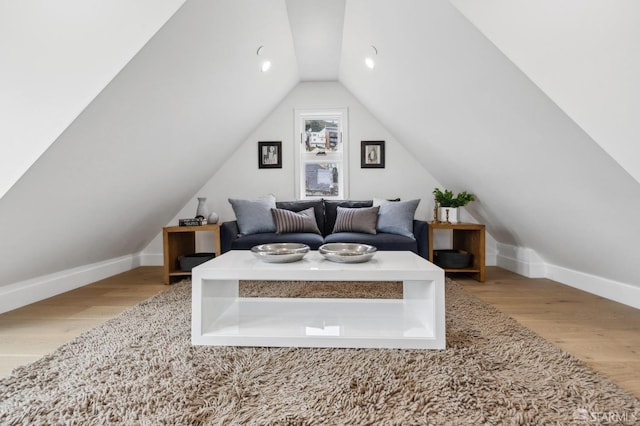 bedroom with vaulted ceiling, wood finished floors, and baseboards