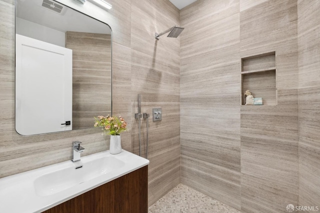 full bathroom featuring vanity, visible vents, and tiled shower