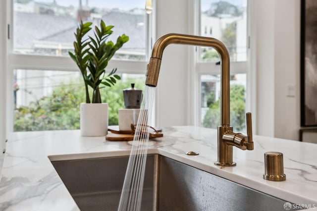 interior details with a sink and light stone countertops